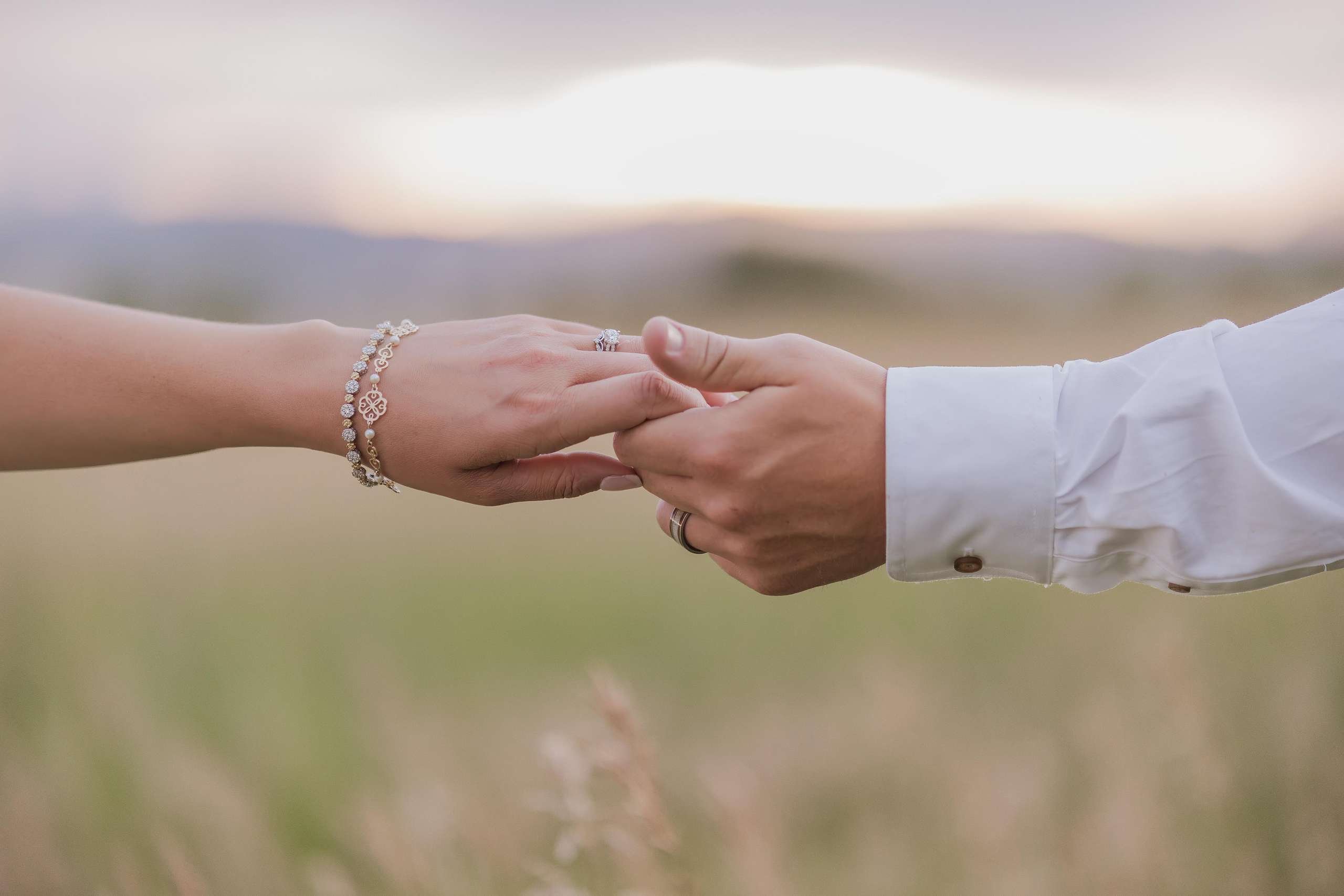 bride and groom holding hands with gtall grass in the background.